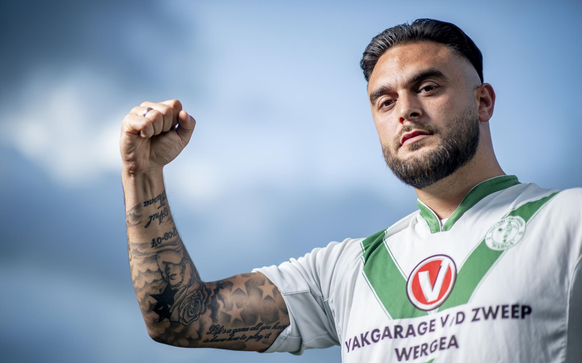 Okan Özçelik toont in het shirt van Warga zijn tatoeages, die de voormalig profvoetballer liet zetten nadat een levertransplantatie zijn leven redde.